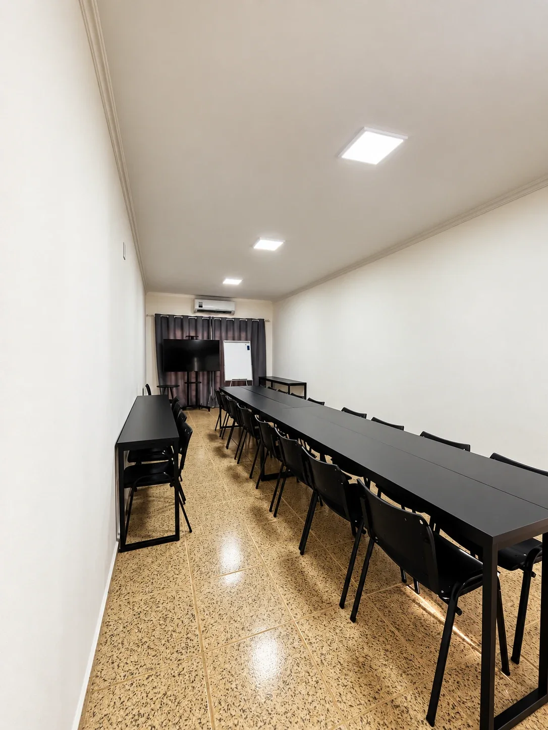 Vista lateral da Sala 7 da Unidade 2 com mesas e cadeiras